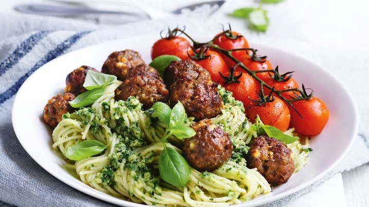 a bowl of Low FODMAP meatballs with pesto spaghetti and tomatoes